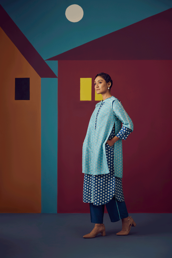 Woman in a polka dot outfit standing in front of a colorful geometric wall.