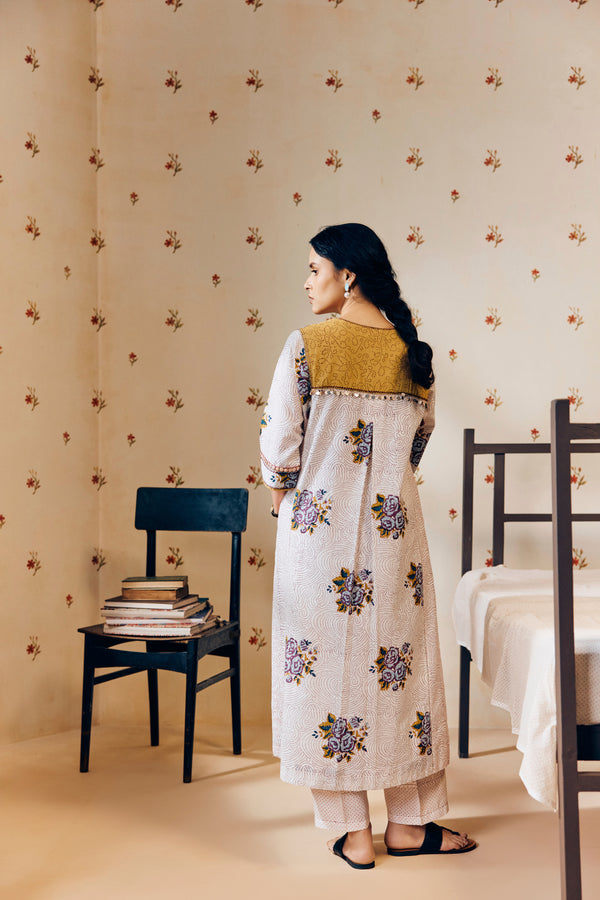 Off-white handwoven khadi cotton tunic featuring a red poppy hand block print, paired with mustard yellow striped pants; an ethnic set blending traditional craftsmanship with contemporary design.




