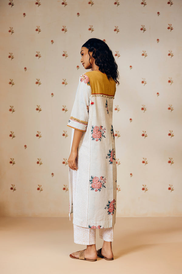 Off-white handwoven khadi cotton tunic with sky blue and pink rose hand block print, paired with mustard bandhani dot printed pants; a handcrafted summer co-ord set made from breathable, natural fabric.