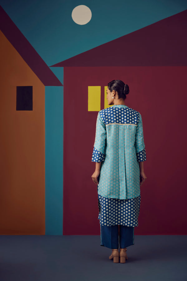 Woman in a polka dot outfit standing in front of a colorful geometric wall.